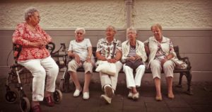 Group of senior women sitting outside on a bench talking