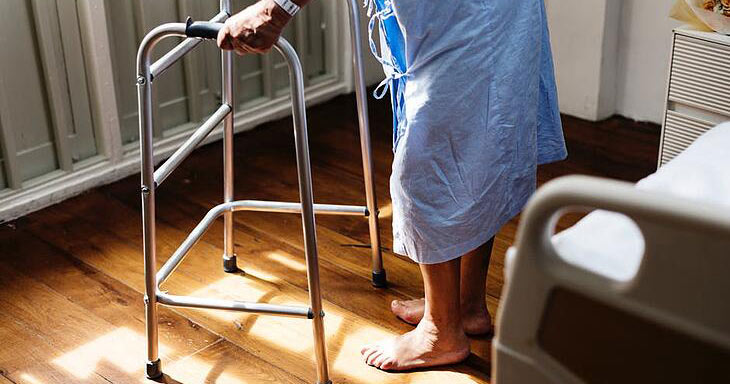 senior in hospital getting up with a walker