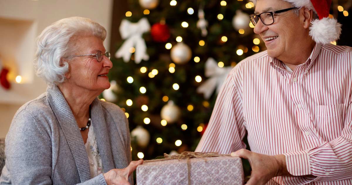 a senior woman exchanging a christmas gift with her adult son