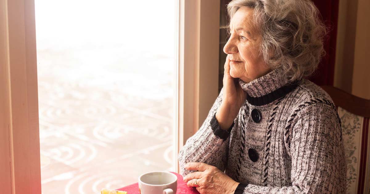 A senior woman sitting the window with a cup o f tea