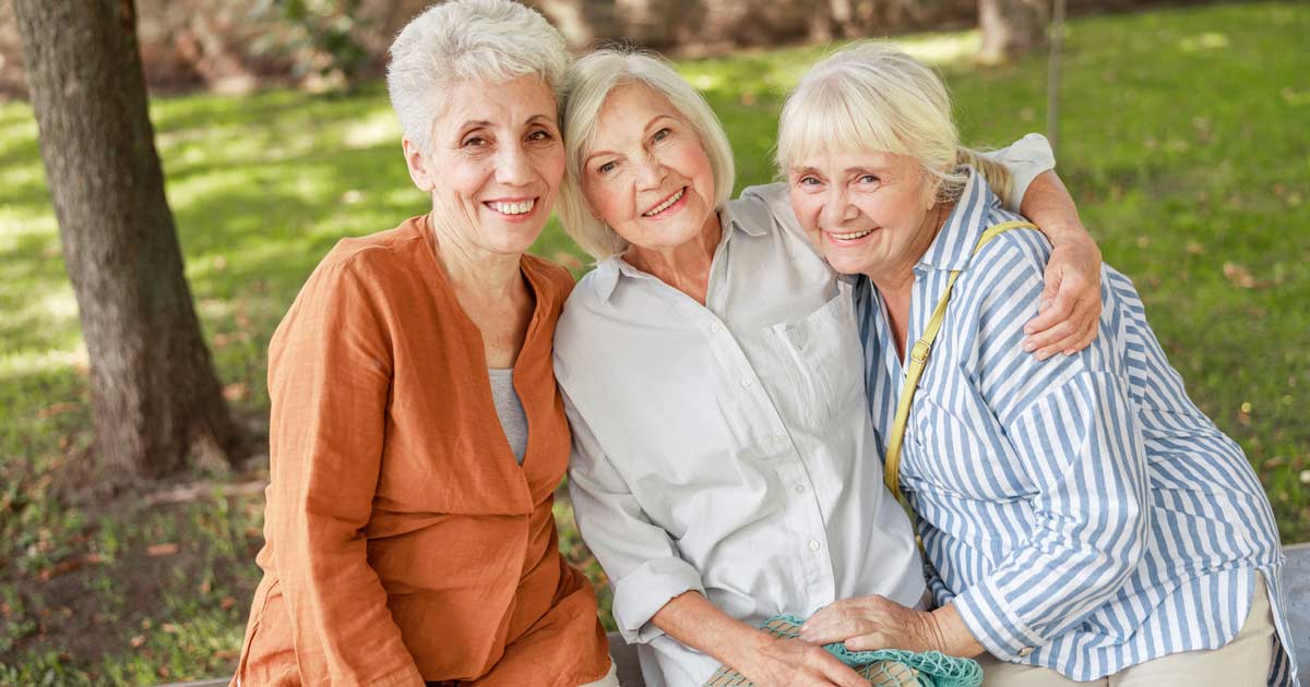Three senior women friends posing for a photo in the park