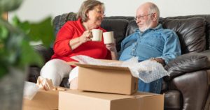 Senior couple sitting on a couch in the middle of moving house