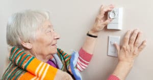 Senior woman adjusting thermostat