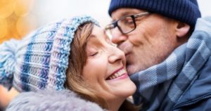close up of happy senior couple kissing in winter