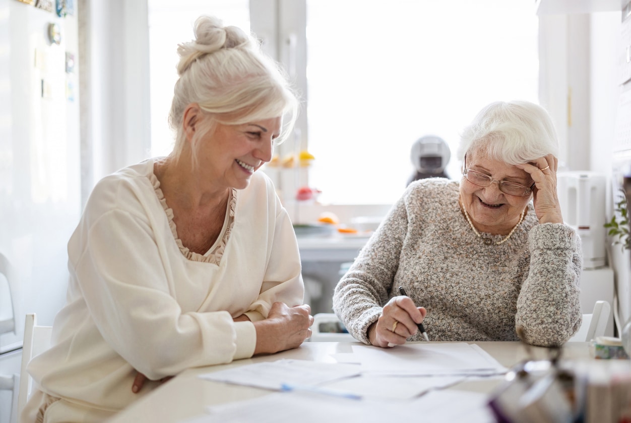 Woman helping her elderly mother preparing financial documents senior parents' finances